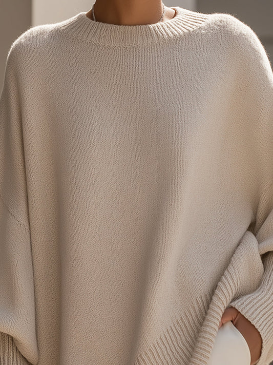 Woman wearing a jeanne | poncho sweater against a light beige background