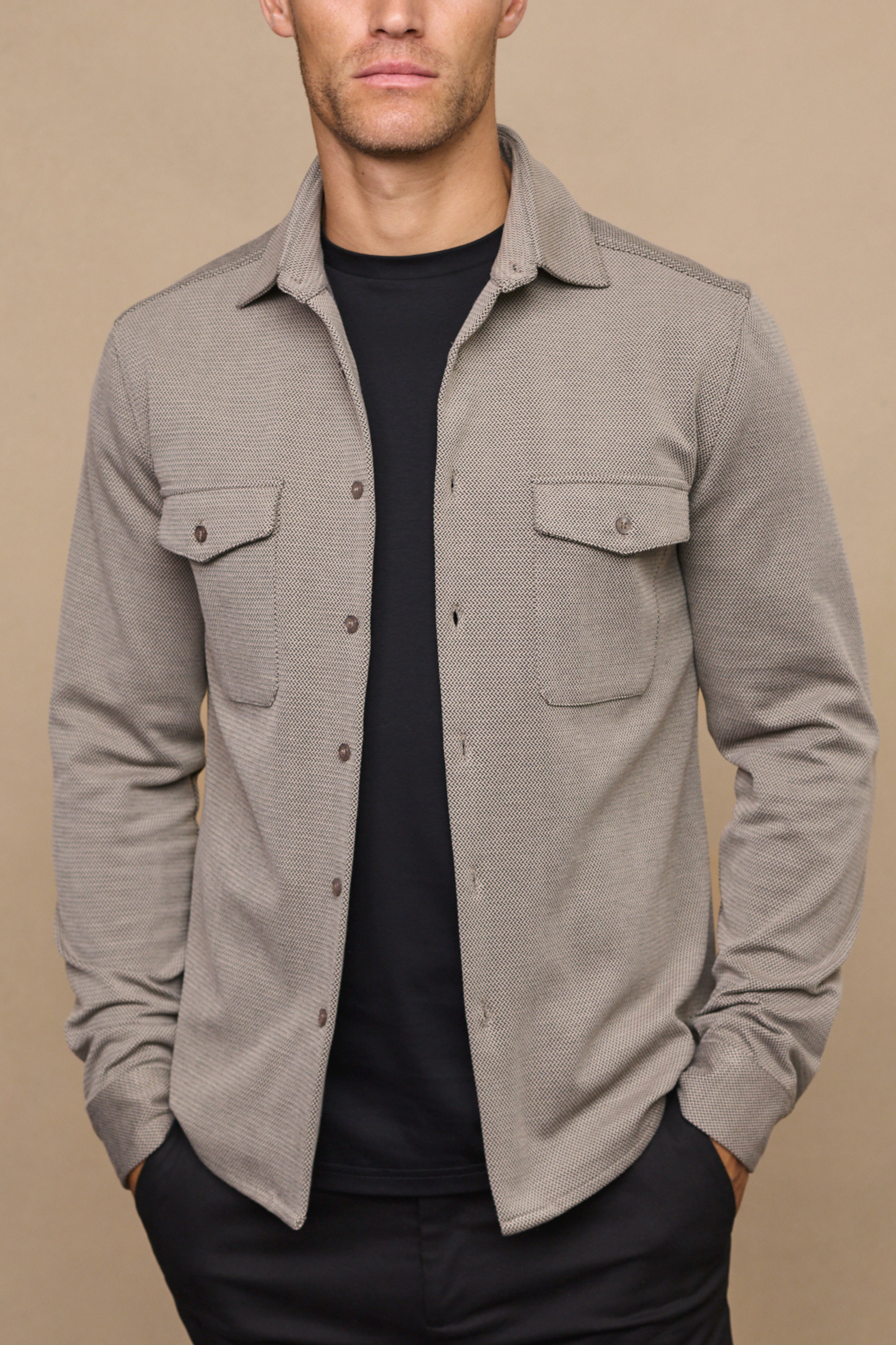 Man wearing a beige overshirt against a clean background