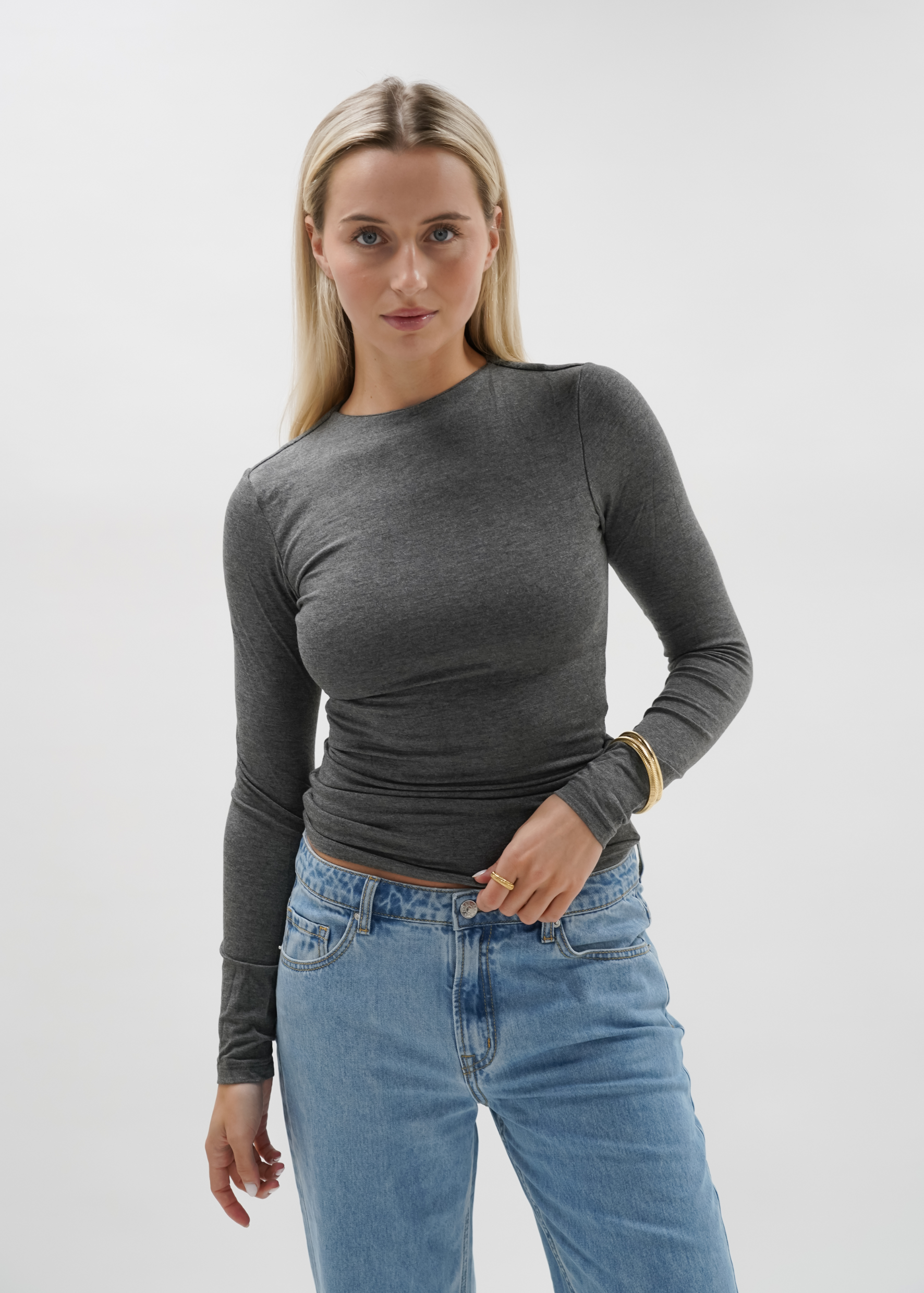 Woman wearing a grey top against a plain background