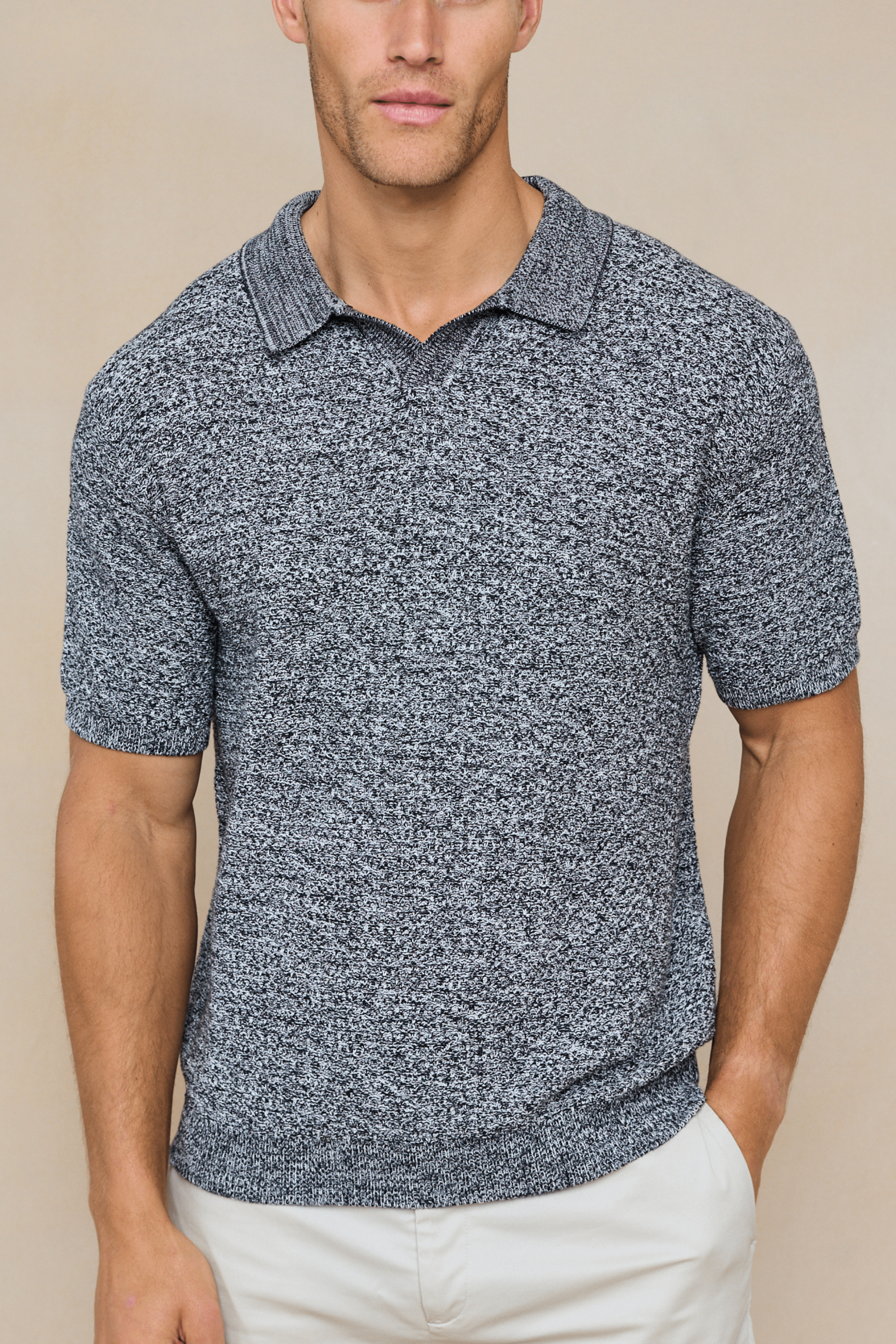 Man wearing a grey marl cotton knit polo by rapha against a clean background