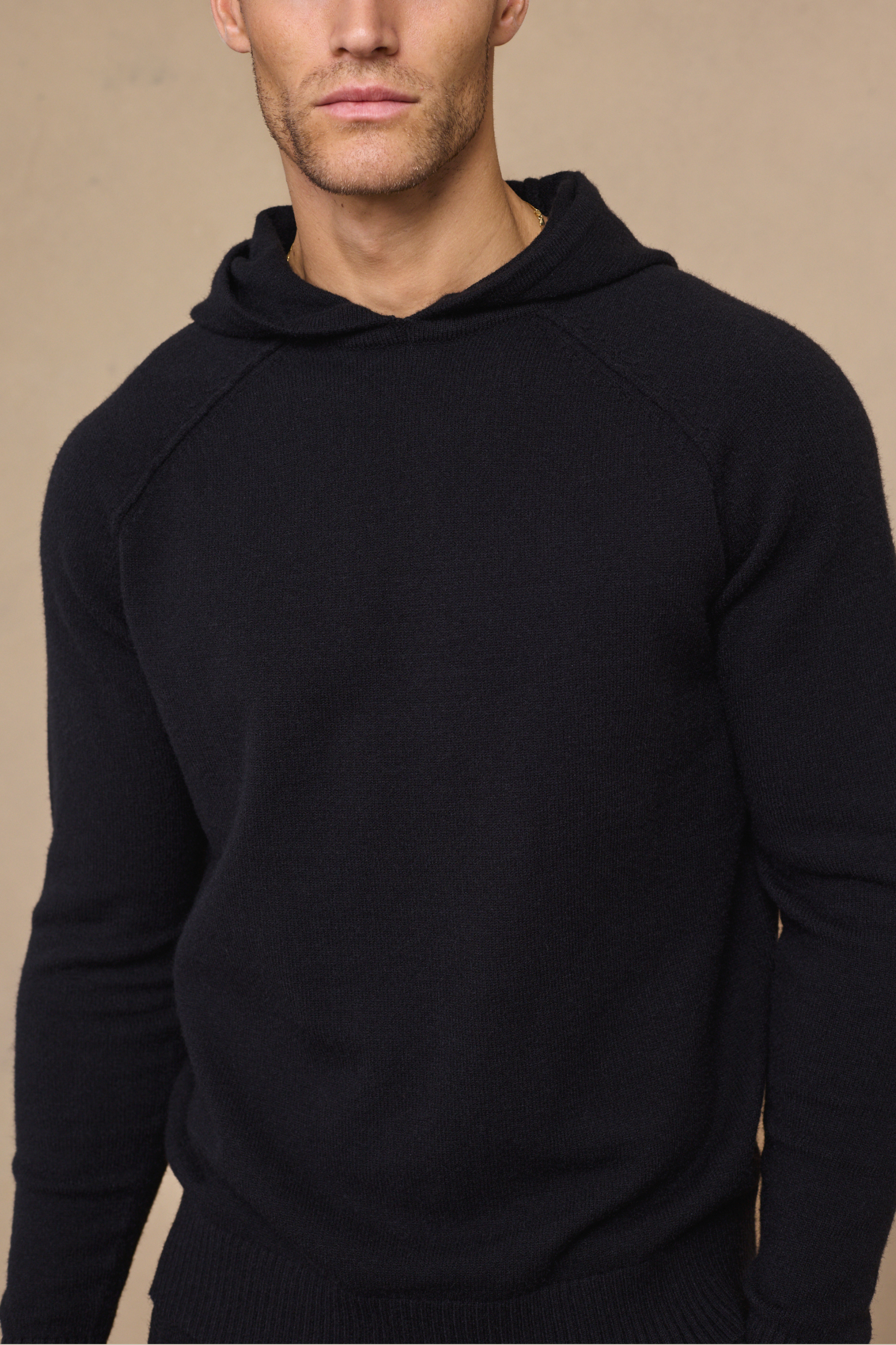 Man wearing a black rowan knit hoodie against a plain background