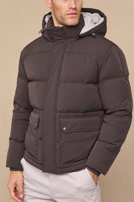 Man wearing an everetto brown down-filled puffer jacket against a neutral studio background