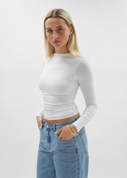 Woman wearing a white top against a plain background