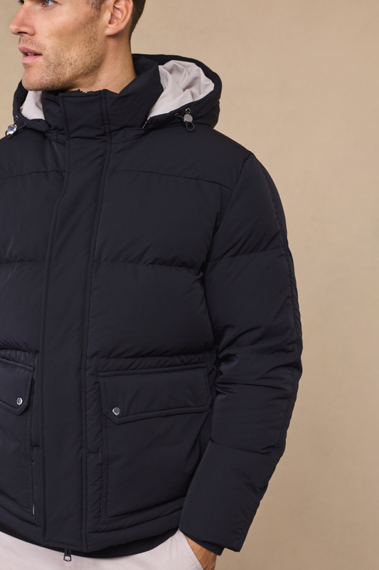 Man wearing an everetto black down-filled puffer jacket against a neutral studio background