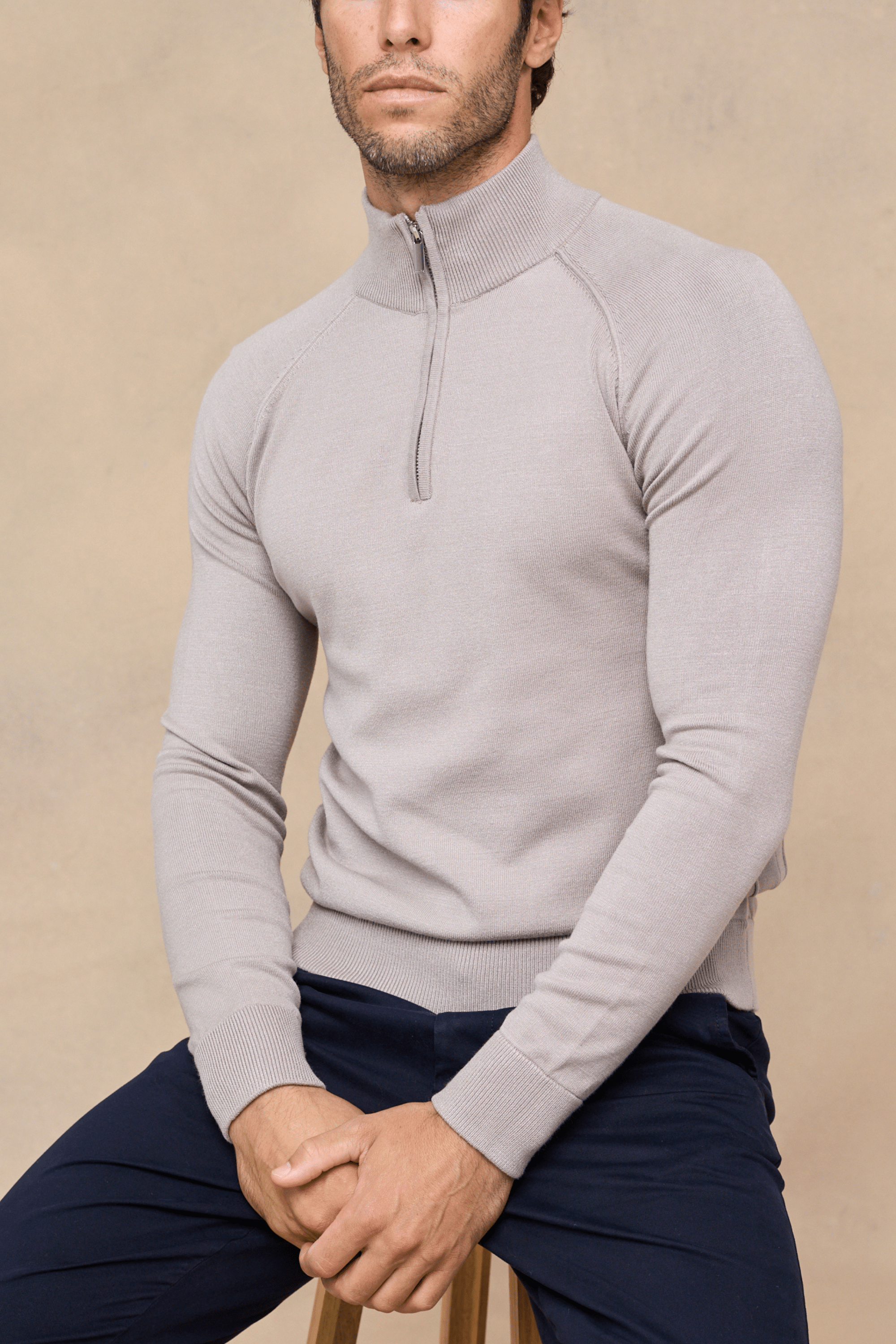Man wearing a half-zip knitted sweater - taupe against a light beige background