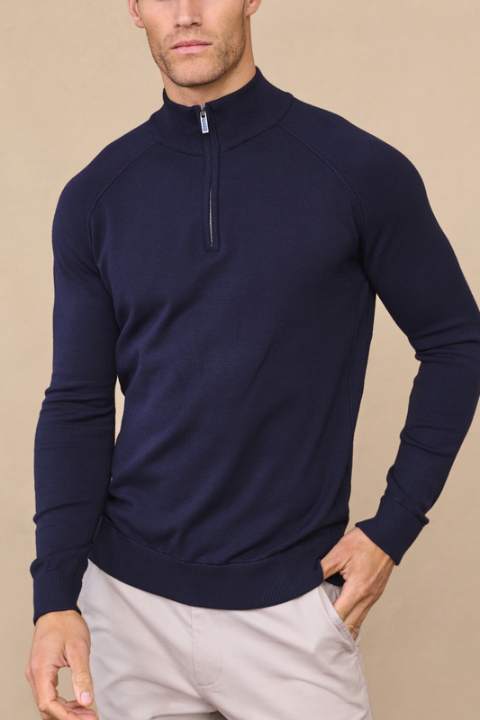 Man wearing a navy alex half-zip knitted sweater against a light beige background