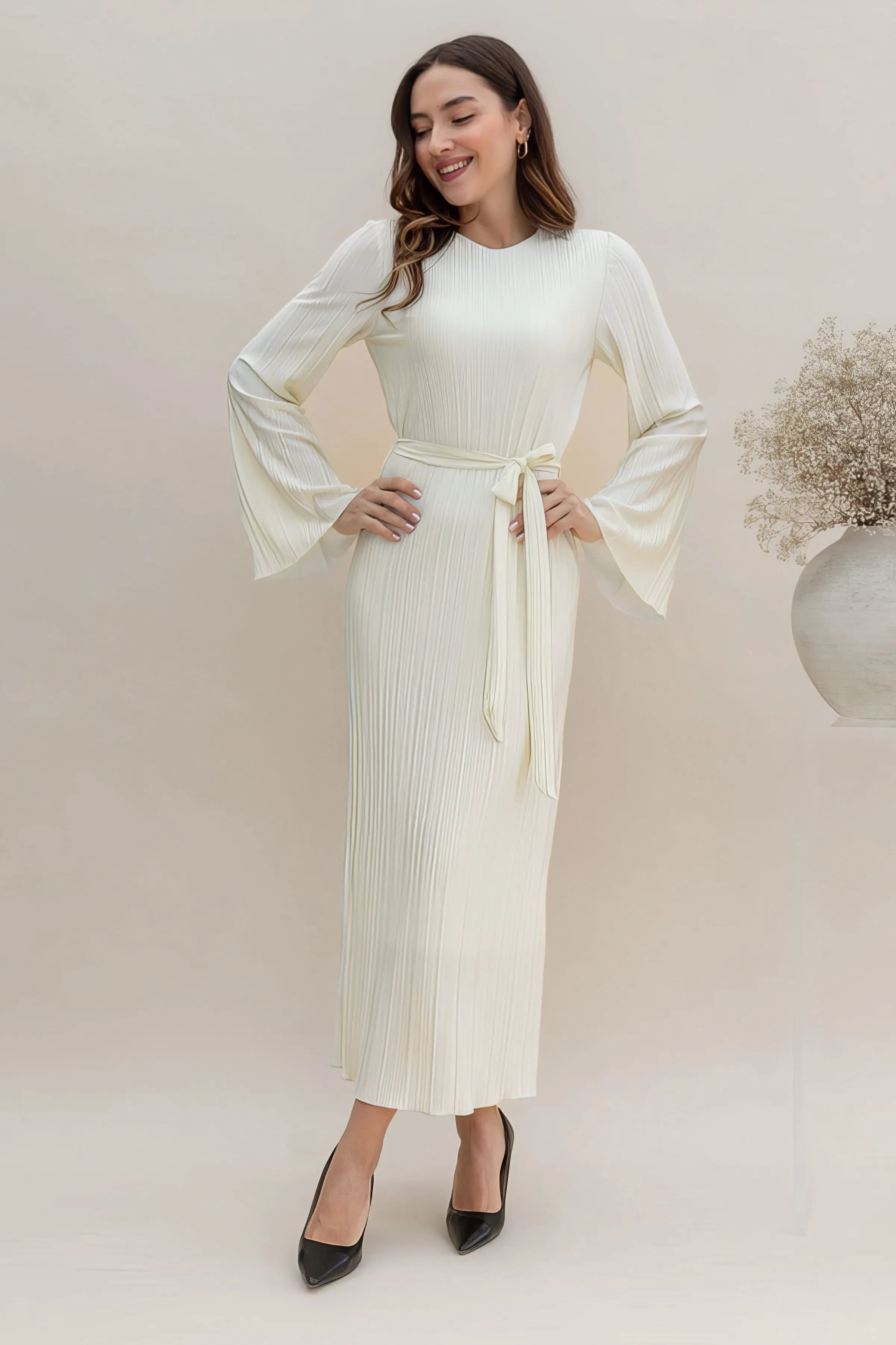 Woman wearing a pleated midi dress against a clean studio background