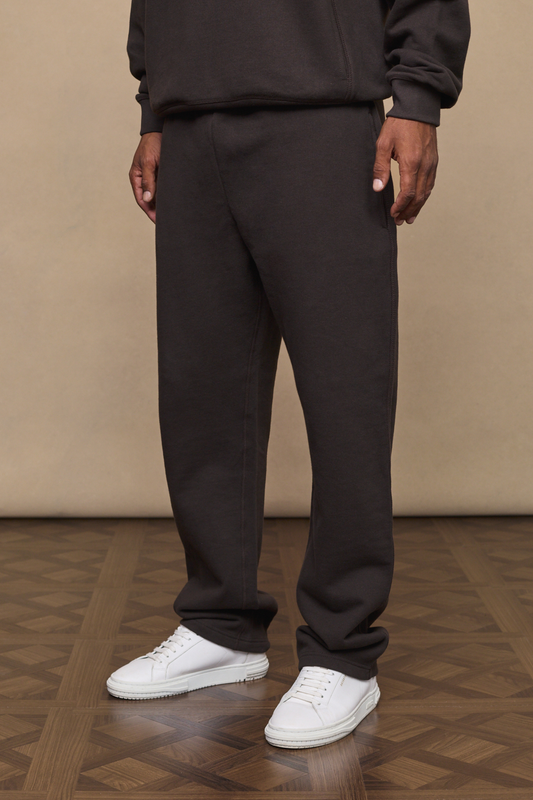 Man wearing a dark brown axel straight leg joggers against a minimal background