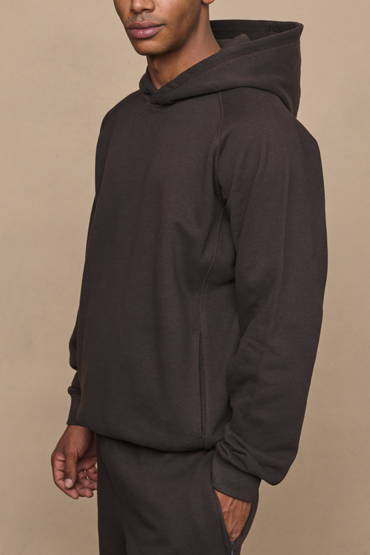 Man wearing a dark brown axel relaxed panel hoodie against a plain background