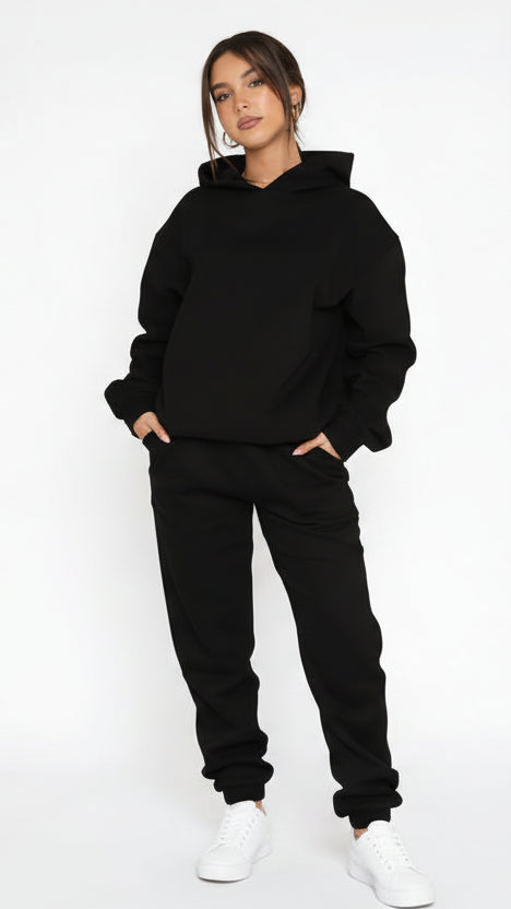 Person wearing a black hoodie and pants on a white background