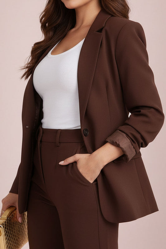Woman wearing a brown suit with a white top against a beige background