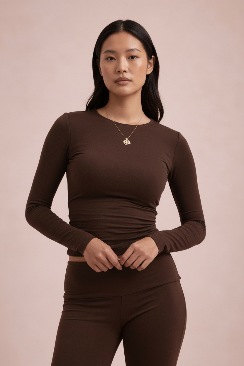 Woman wearing a brown long-sleeve top and pants against a beige background