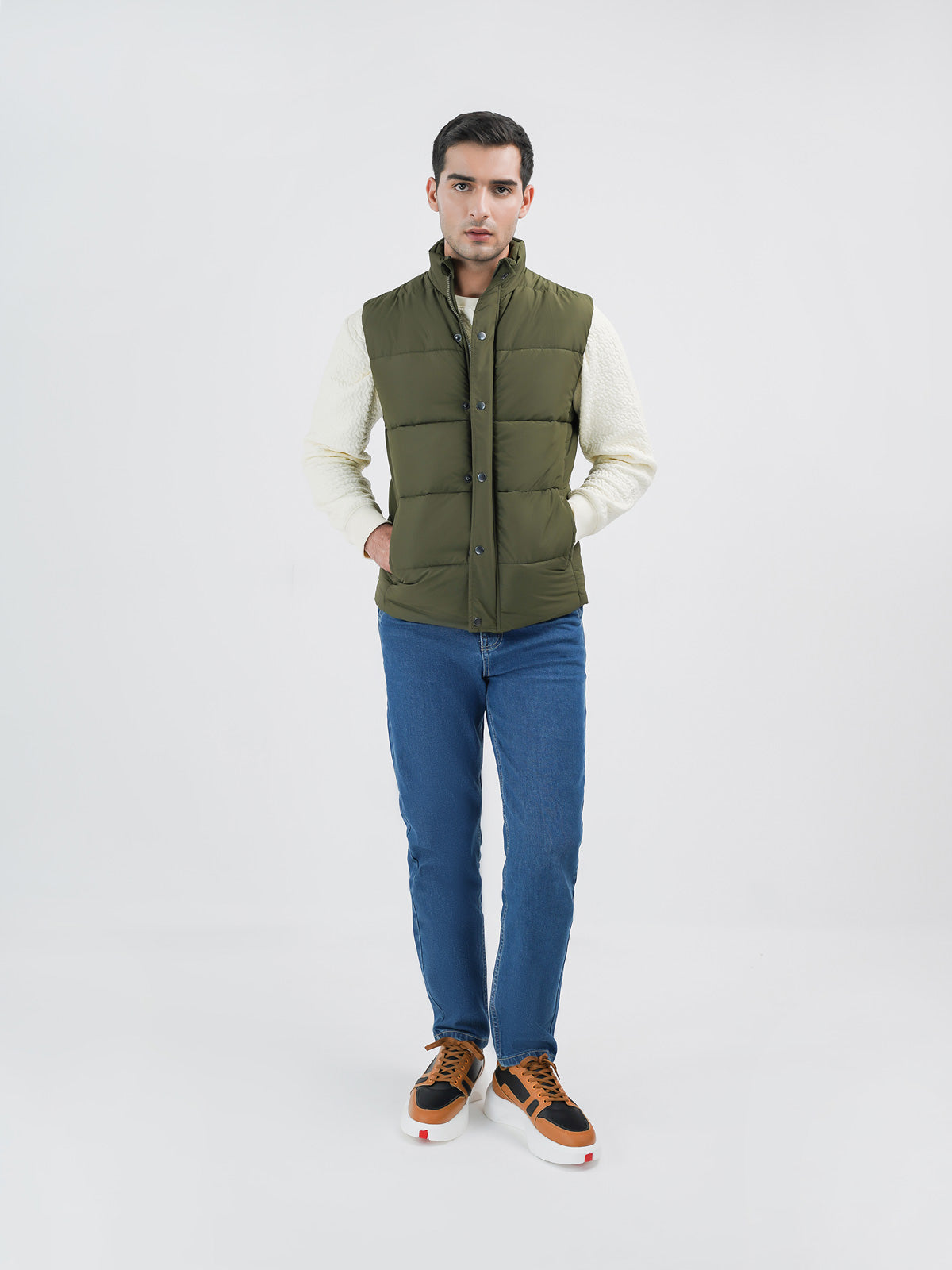 Man wearing an olive puffer jacket against a clean white background