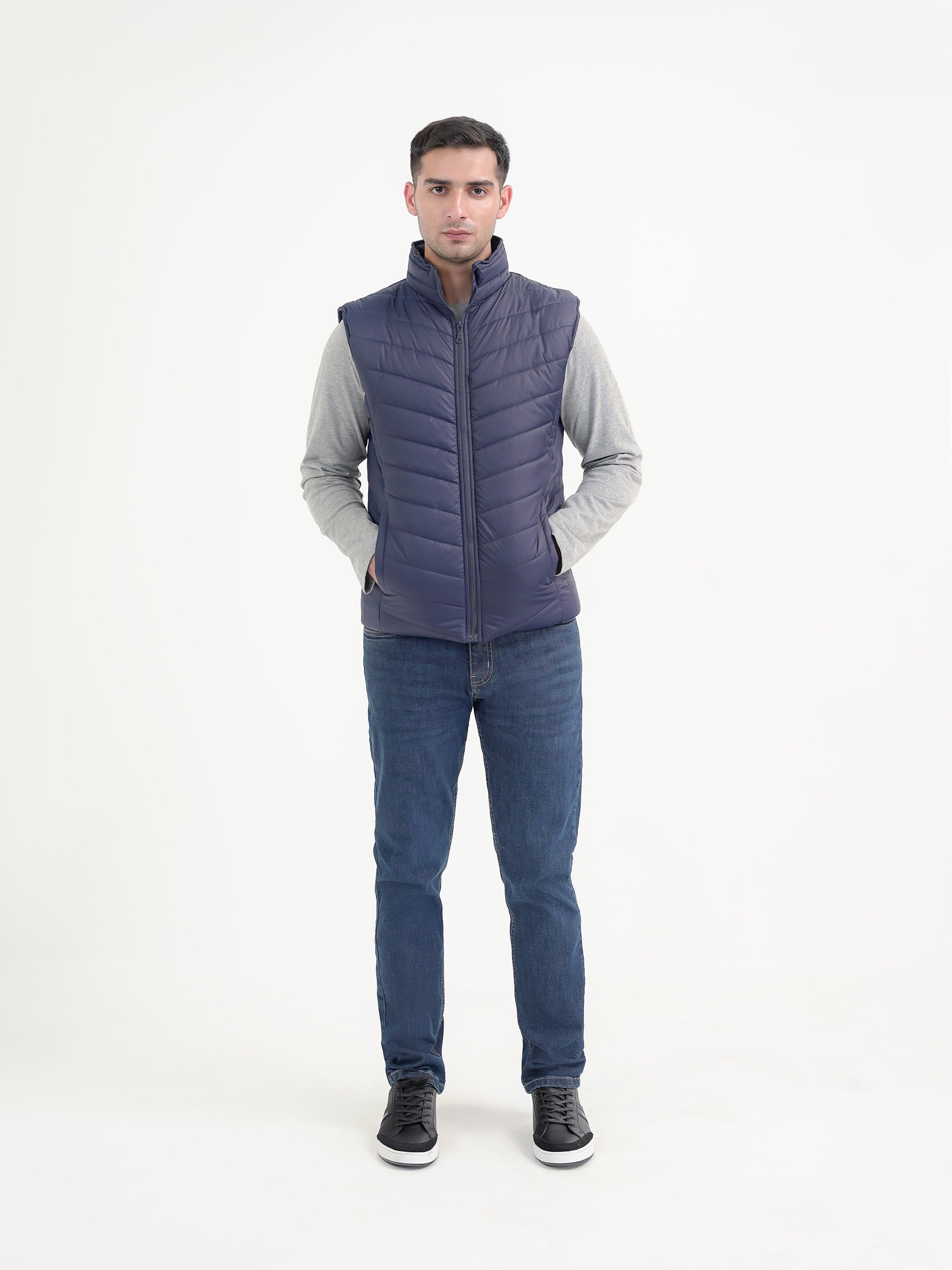 Man wearing a navy puffer jacket against a clean white background