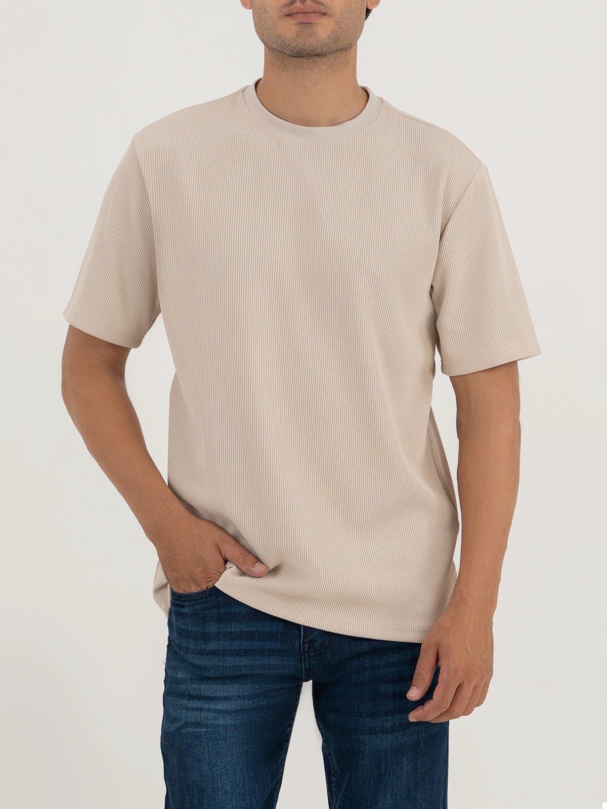 Man wearing a beige t-shirt against a plain white background