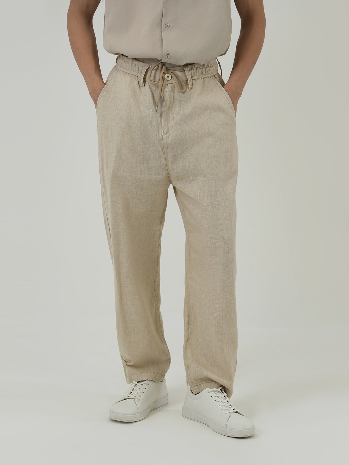 Man wearing a beige trousers against a plain background