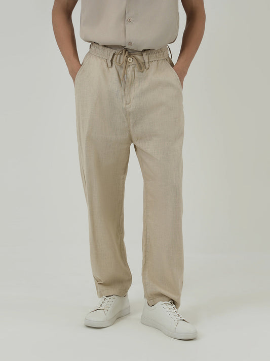 Man wearing a beige trousers against a plain background