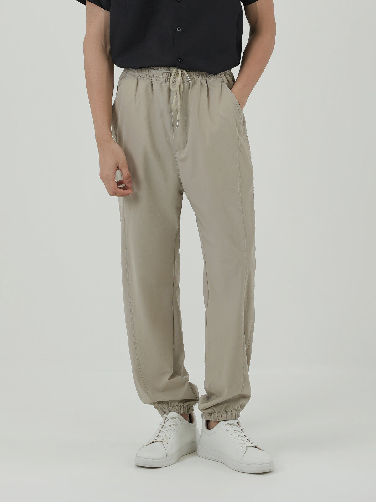Man wearing a beige trousers against a plain background