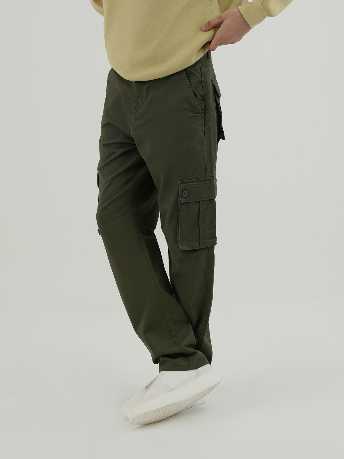 Man wearing an olive cargo trousers against a plain background
