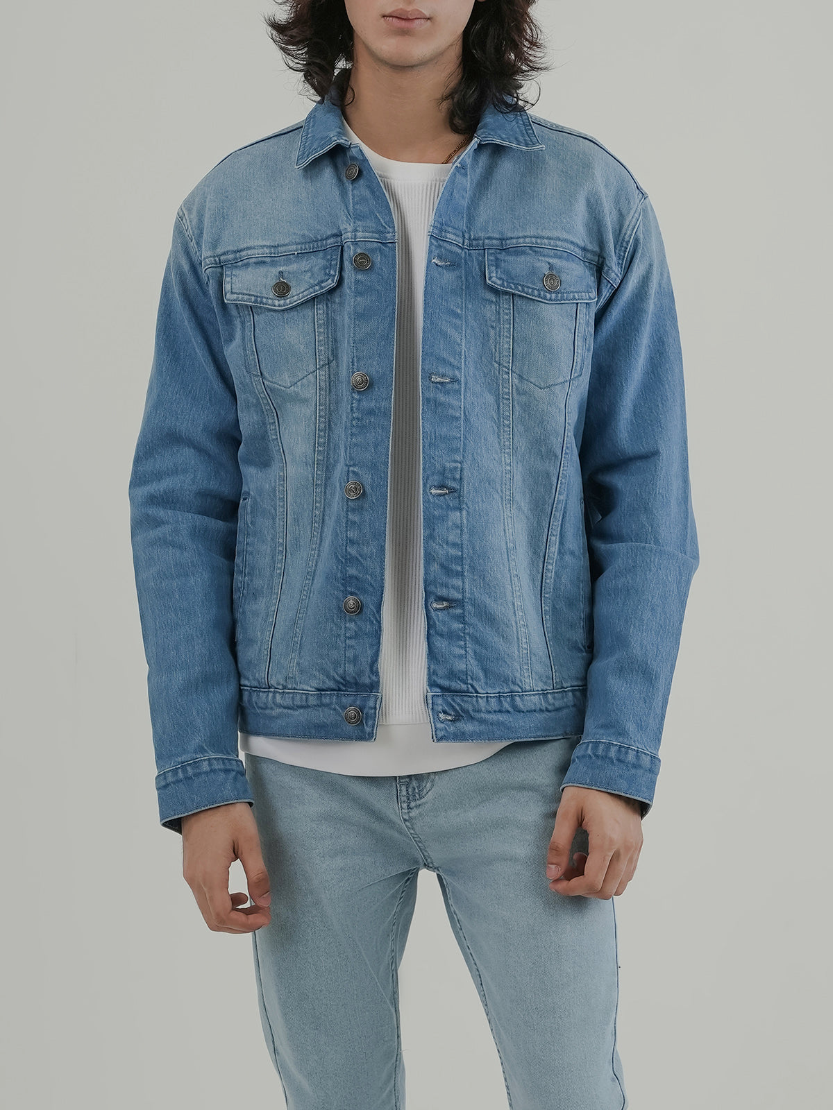 Man wearing a light blue denim jacket against a clean white background
