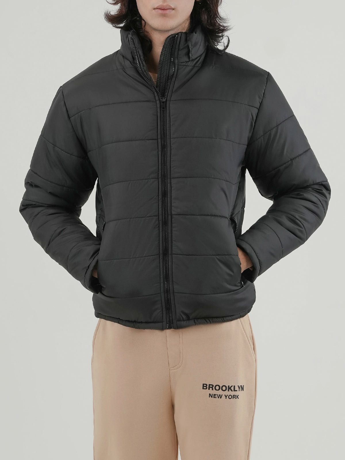 Man wearing a black puffer jacket against a clean white background