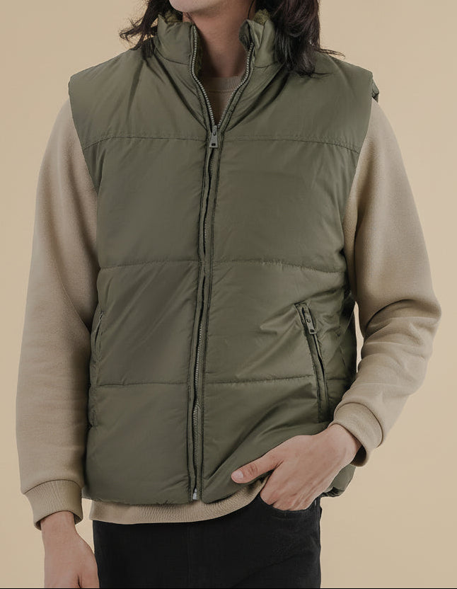 Man wearing an olive puffer jacket against a clean white background