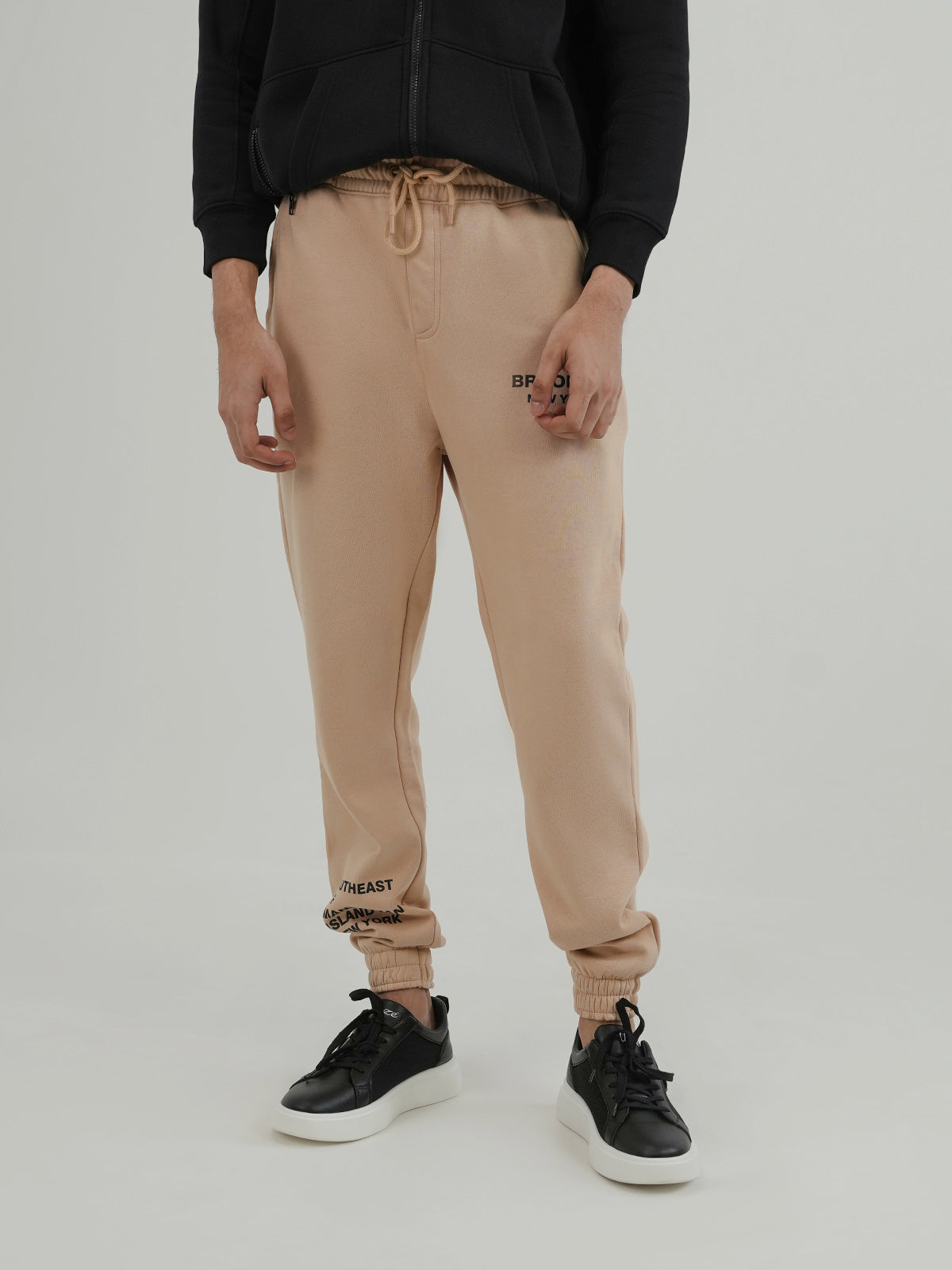 Man wearing a beige trousers against a plain background