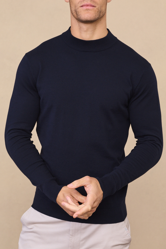 Man wearing a navy noah lightweight crew neck sweater against a light beige background